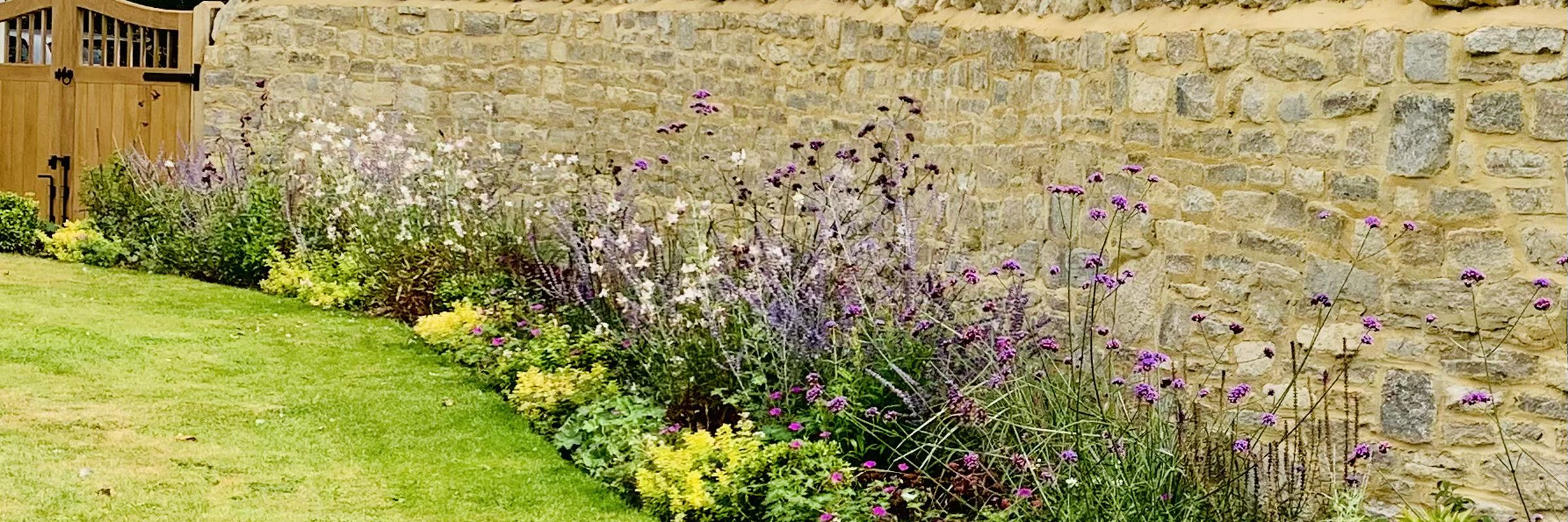 A long summer border running the length of a mellow stone wall